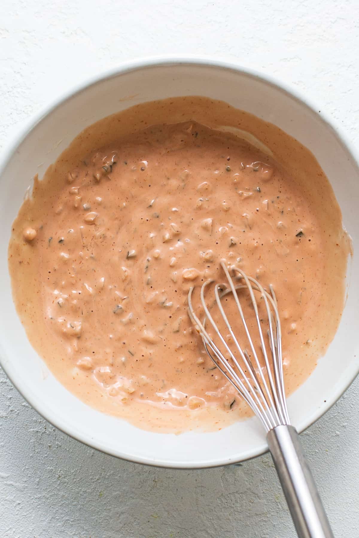 A bowl of sauce with a whisk in it.