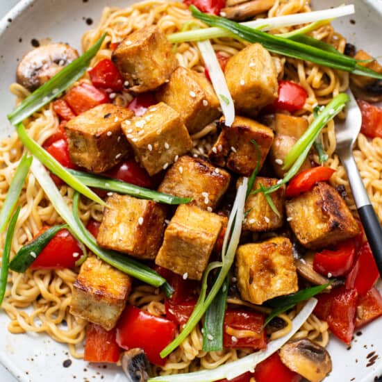 Asian tofu noodles with mushrooms and tomatoes on a plate.