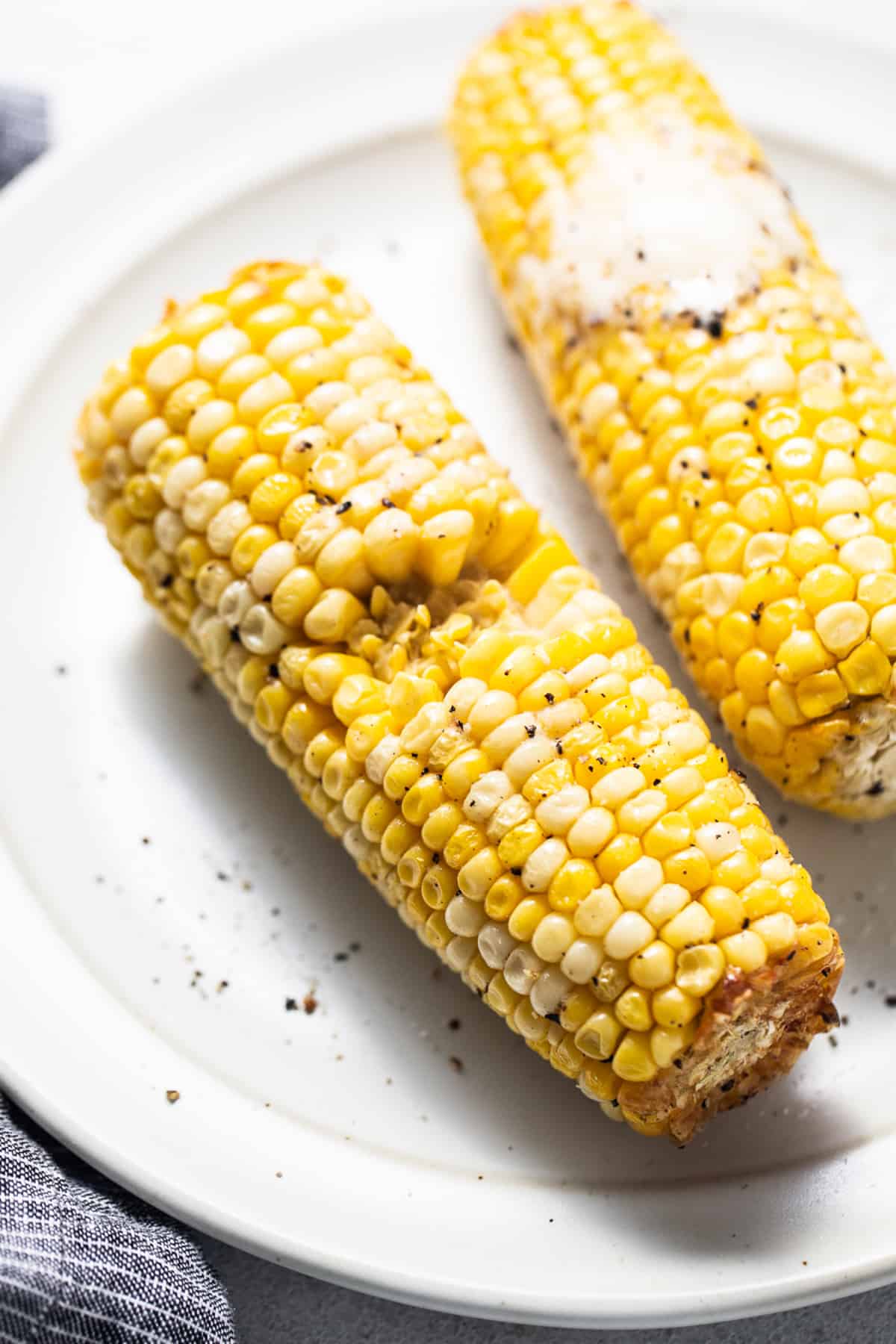 two corn on the cob on a white plate.