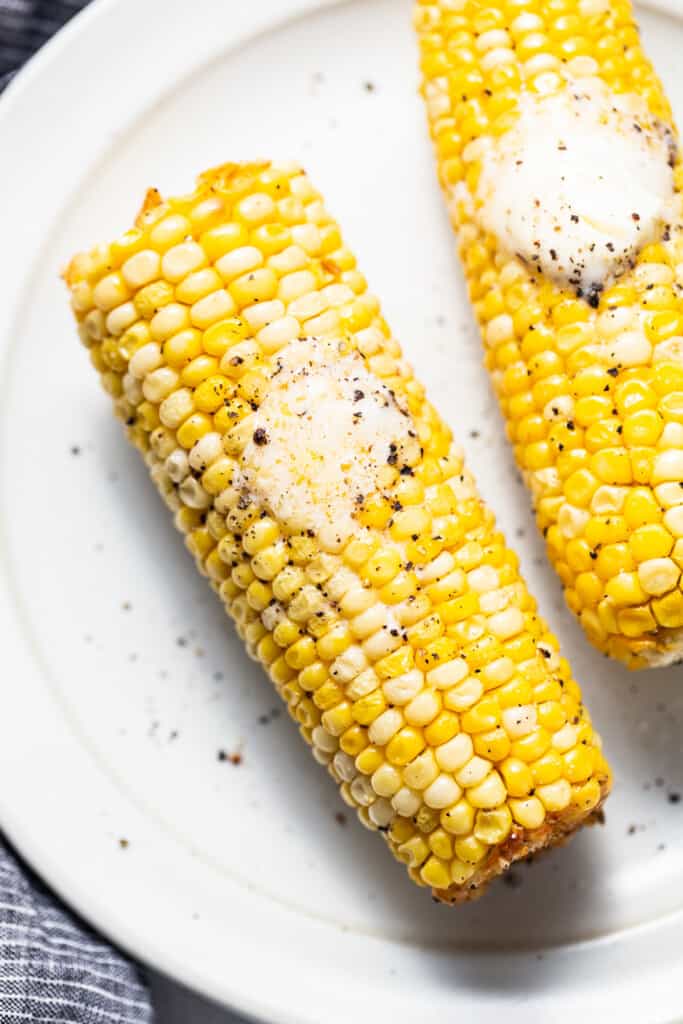 two corn on the cob on a white plate.