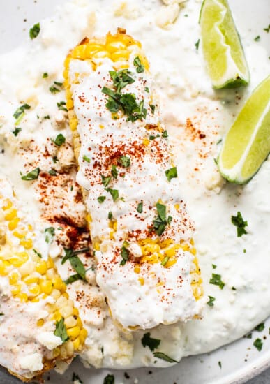 Air fryer elote on a plate with slices of lime.