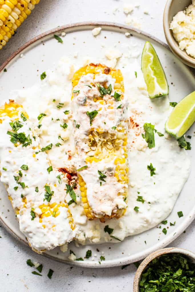Air fryer elote with a bite taken out of it on a plate.