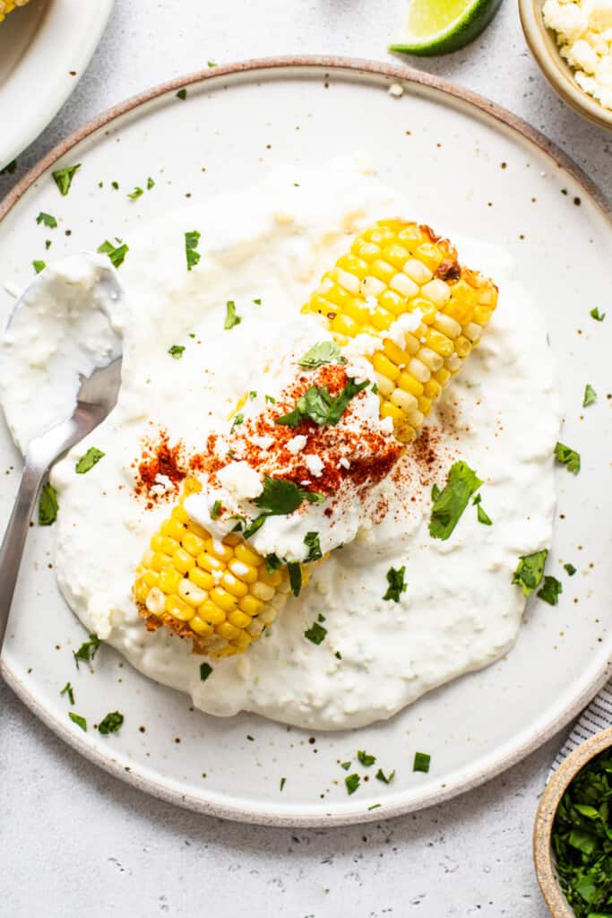 Air fryer elote on a plate with a spoon.