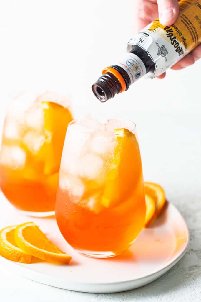 Bitters being poured in an aperol spritz.