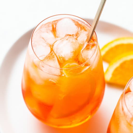 Aperol spritz in a glass with a straw.