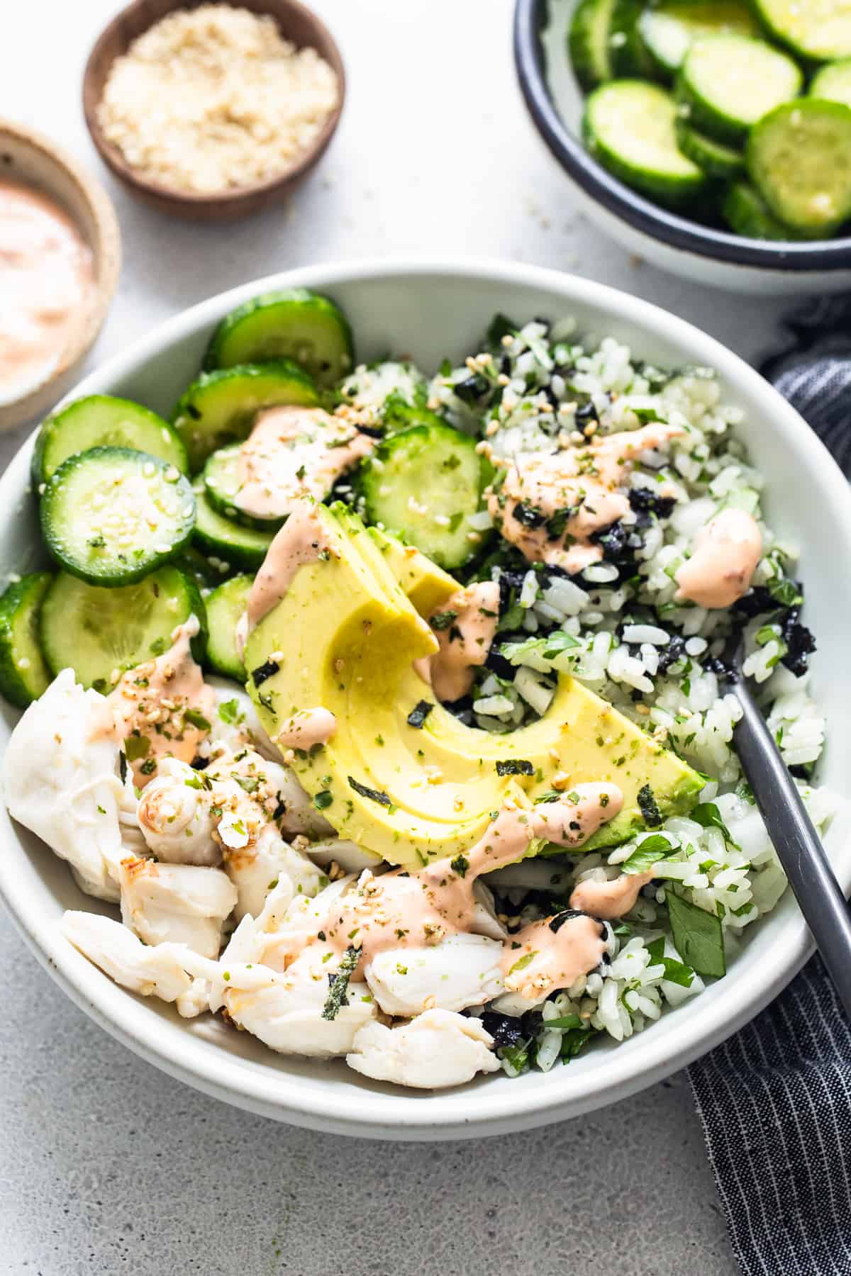 A white bowl with a bowl of rice and cucumbers.