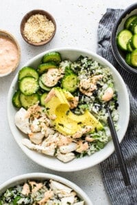 A bowl of salmon and cucumber salad with dressing.