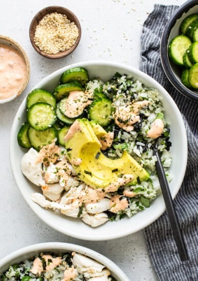 A bowl of salmon and cucumber salad with dressing.