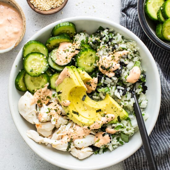 A bowl of salmon and cucumber salad with dressing.