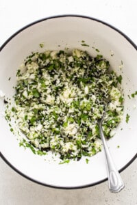 A white bowl filled with greens and a spoon.