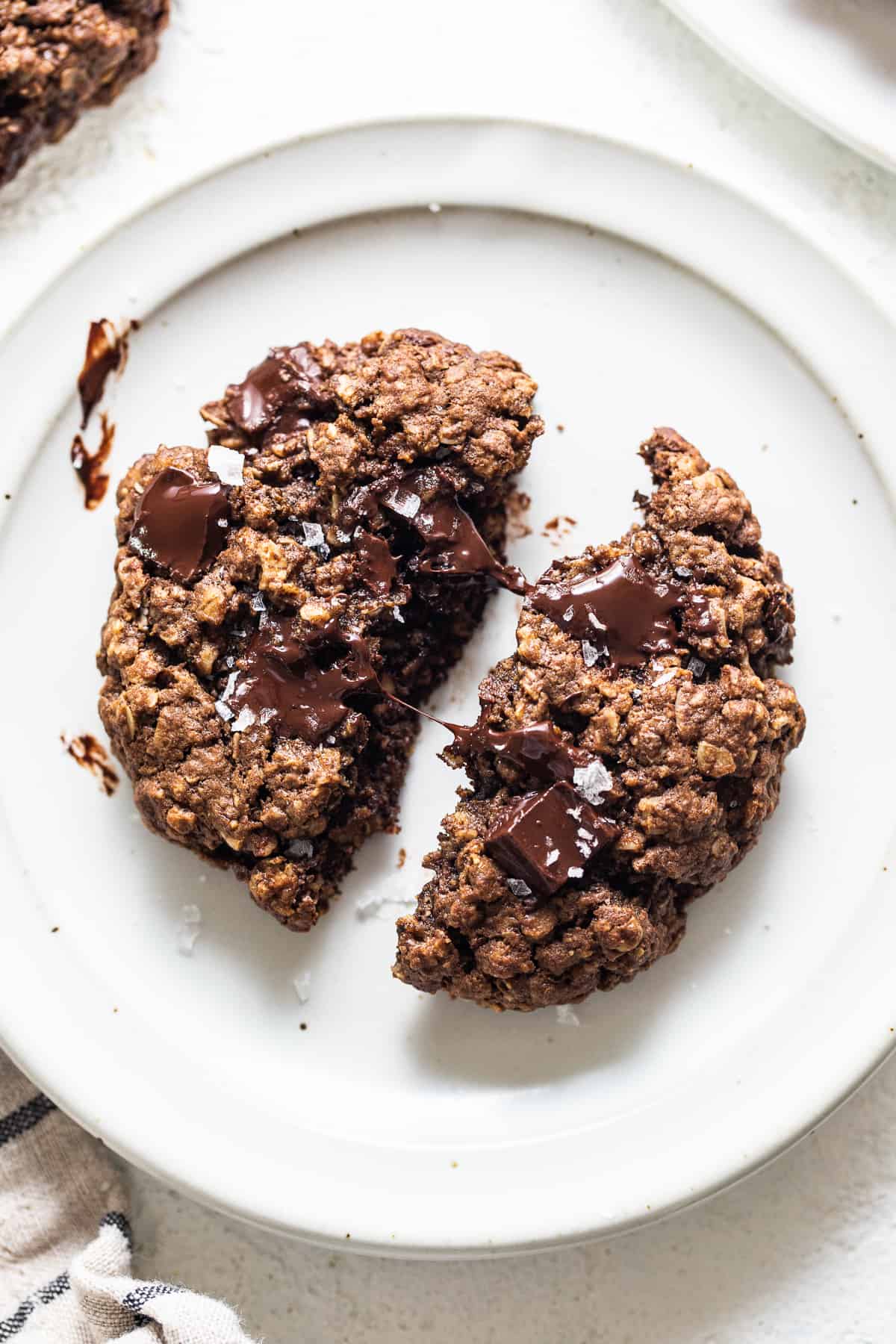 A plate of chocolate oatmeal cookies with a bite taken out.