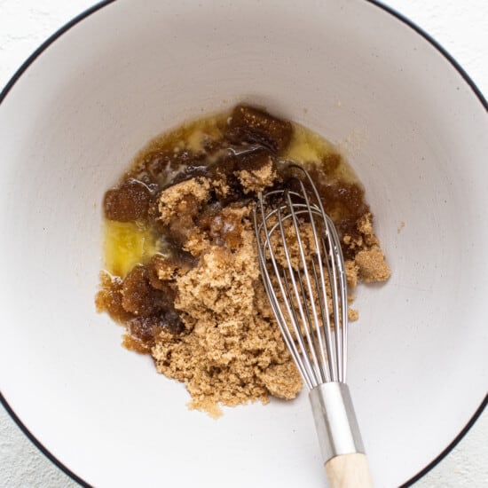 A bowl with a whisk and brown sugar in it.