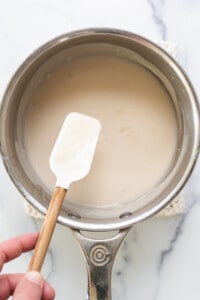 a person holding a spatula in a saucepan.