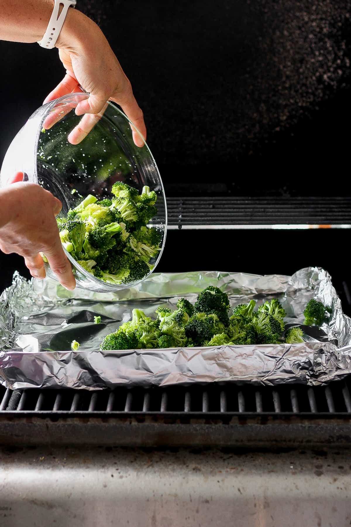 a person is putting broccoli in a bowl.