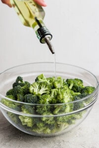 a bowl of broccoli and a bottle of olive oil.