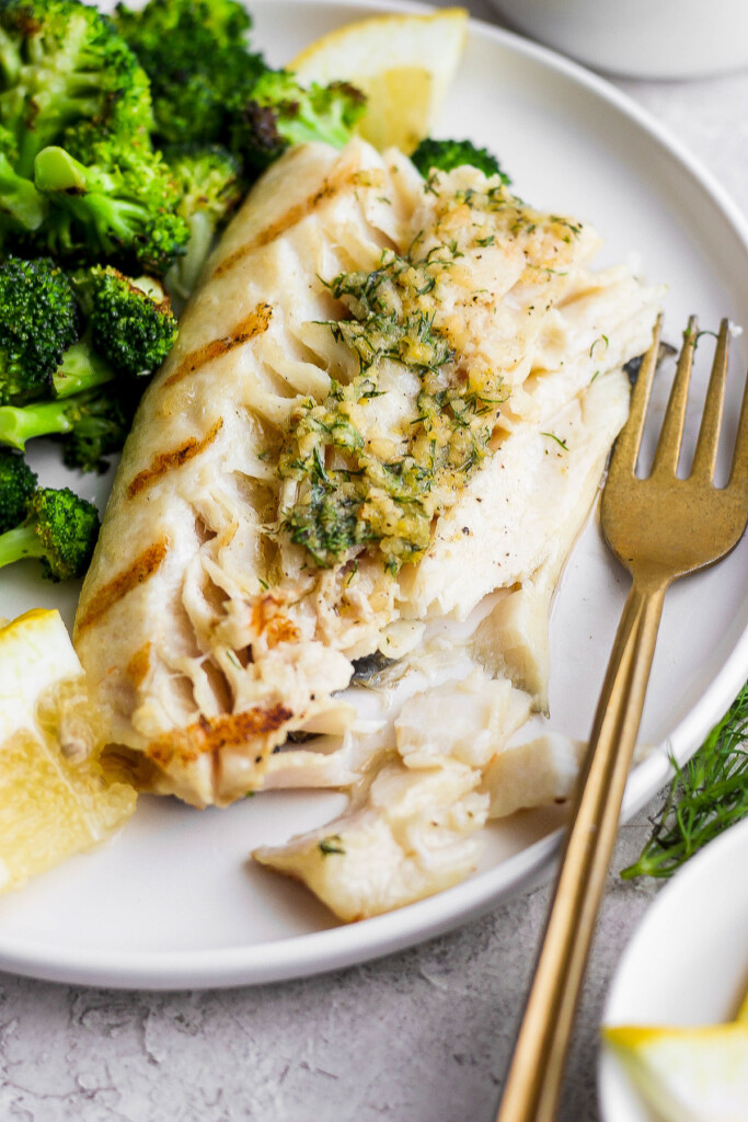 Grilled fish on a plate with broccoli.