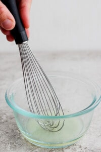 whisking fish marinade in a bowl.