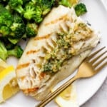 Grilled fish on a plate with broccoli.