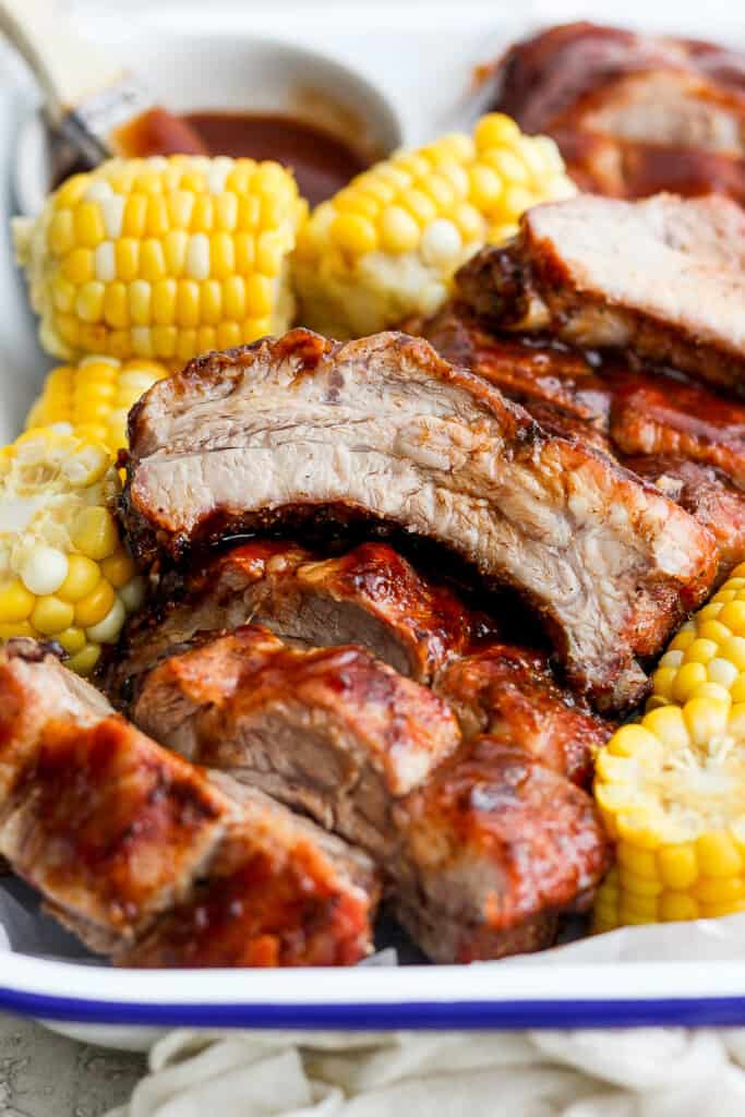 Grilled ribs on a plate with corn on the cob.