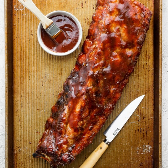 a bbq ribs on a tray with ketchup and a knife.