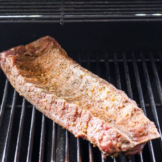 a piece of meat is cooking on a grill.