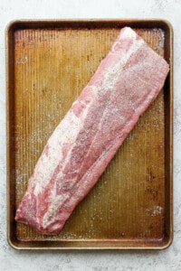 a piece of raw meat sitting on top of a wooden cutting board.