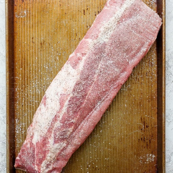 a piece of raw meat sitting on top of a wooden cutting board.