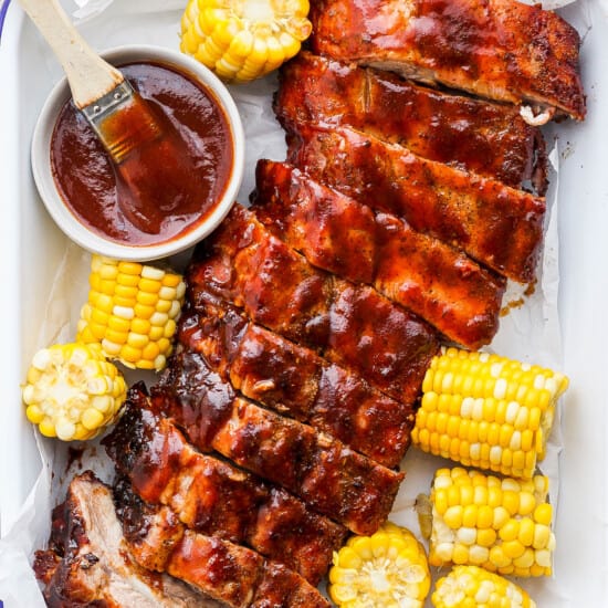bbq ribs and corn on the cob with bbq sauce.