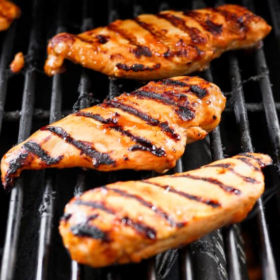 a close up of a grill with chicken on it.