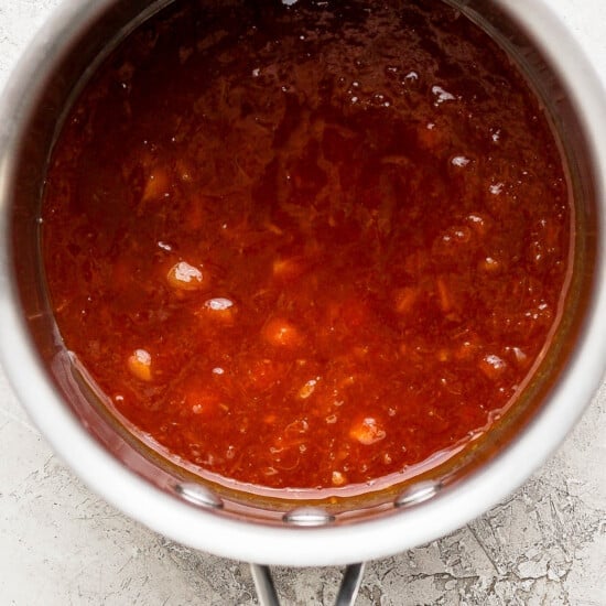 a pot filled with red sauce on top of a counter.