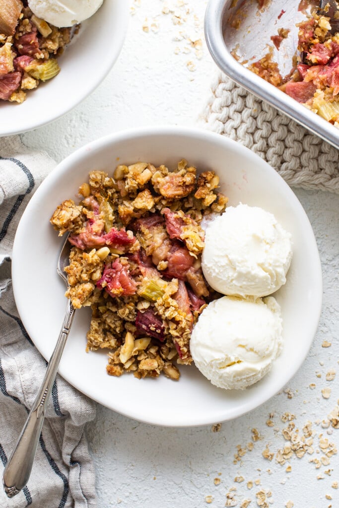 A bowl of cranberry crisp with ice cream and berries.