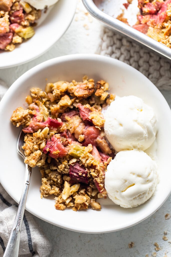 A bowl of cranberry crisp with ice cream and berries.