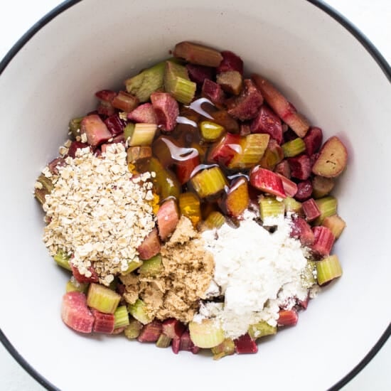 Rhubarb and oats in a bowl on a white surface.