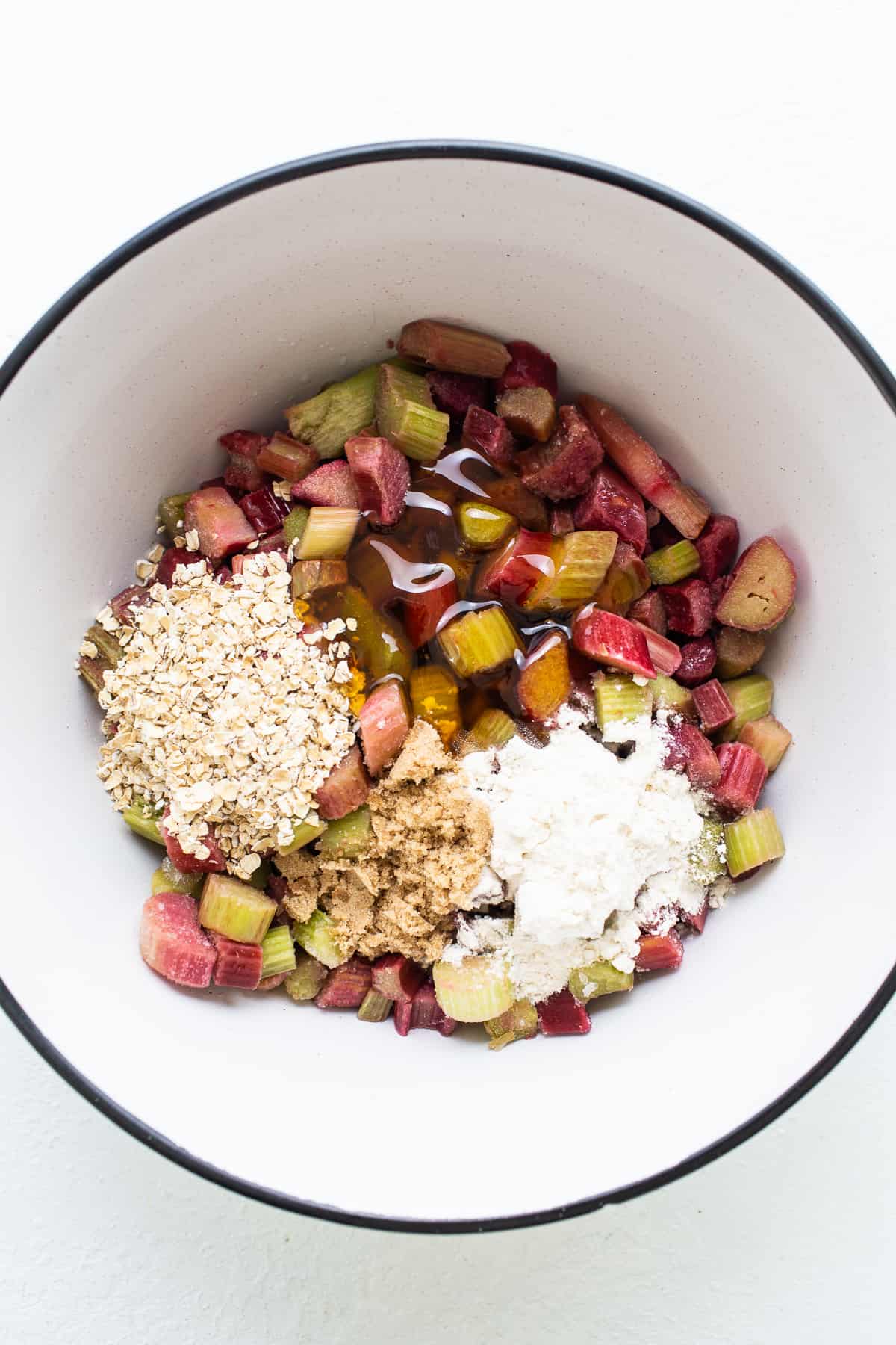 Rhubarb and oats in a bowl on a white surface.