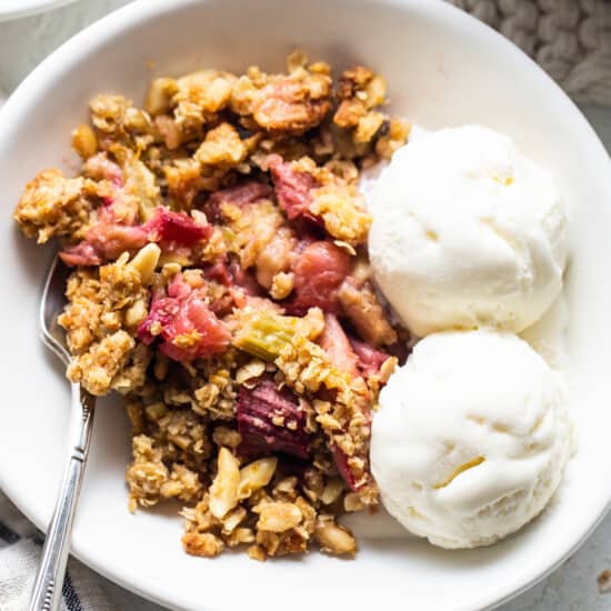 A bowl of rhubarb crisp with ice cream and granola.