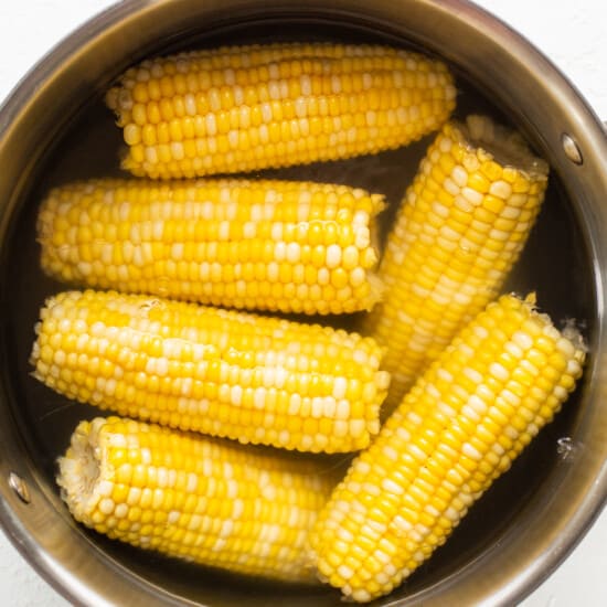 Corn on the cob in a metal bowl.