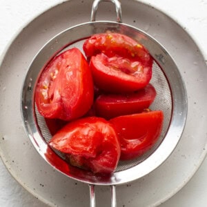 ripe tomatoes in a metal strainer.