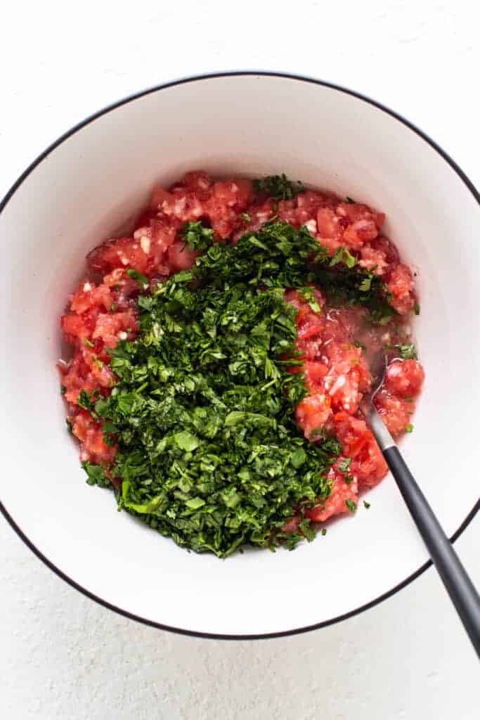 a bowl with tomatoes and herbs in it.