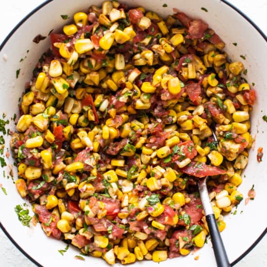 corn salsa in a white bowl with a fork.