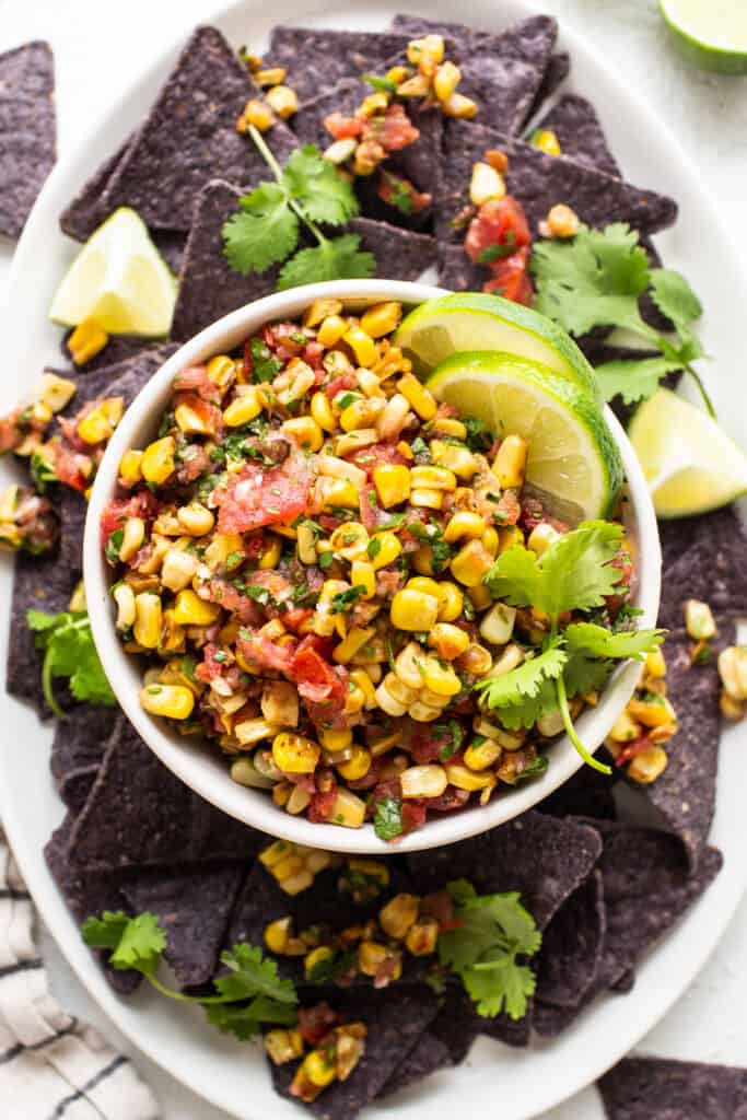 mexican corn salsa on a white plate with tortilla chips.