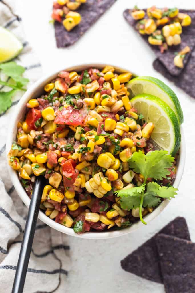 mexican corn salad in a bowl with tortilla chips.