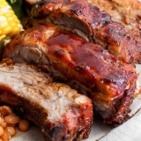 a plate with meat, beans, corn and a salad.
