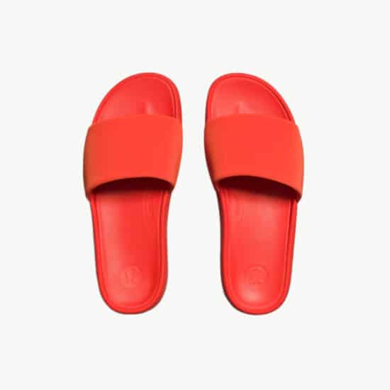 A pair of red slide sandals on a white background.