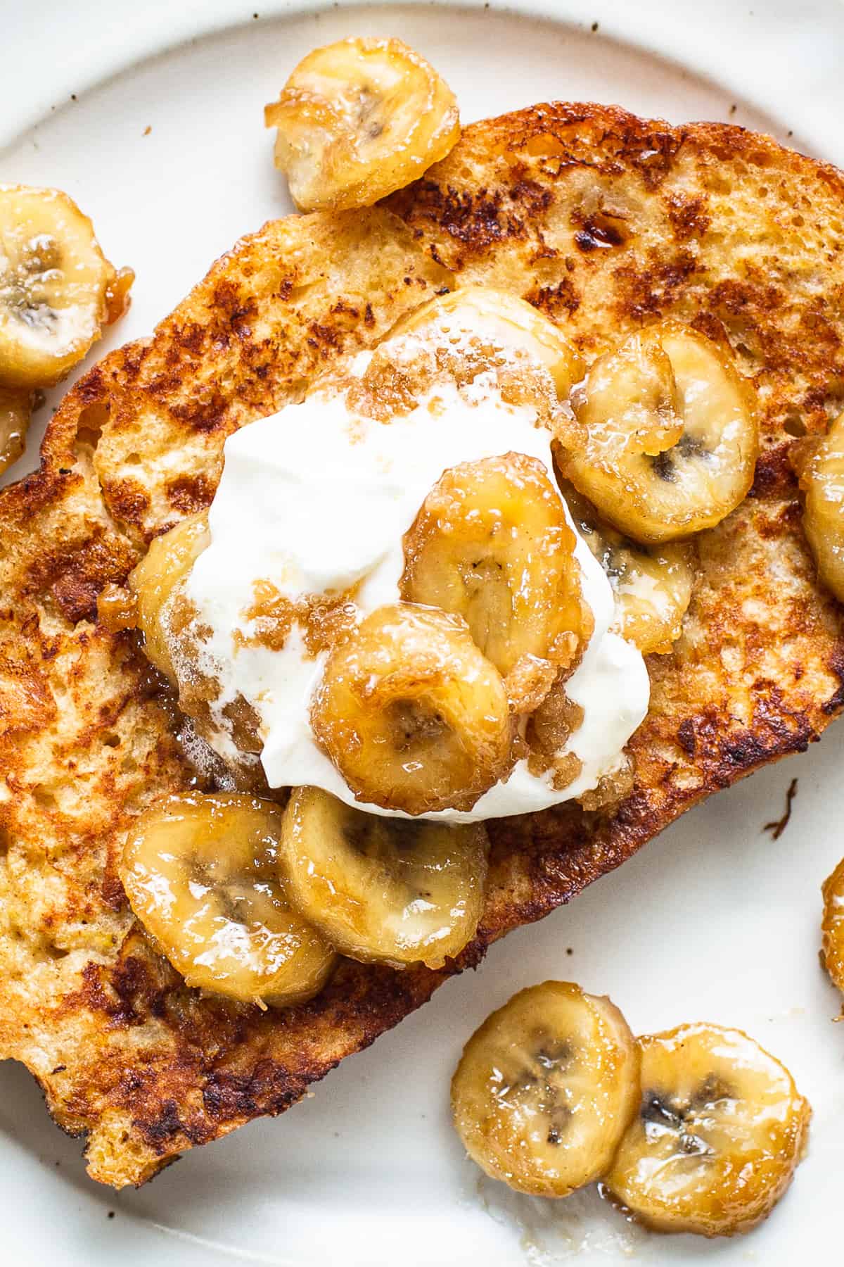 A plate of french toast with banana slices and whipped cream.