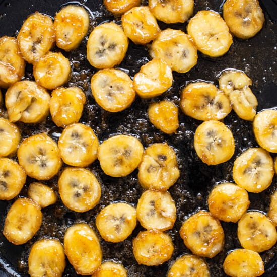 Sliced bananas are being fried in a skillet.
