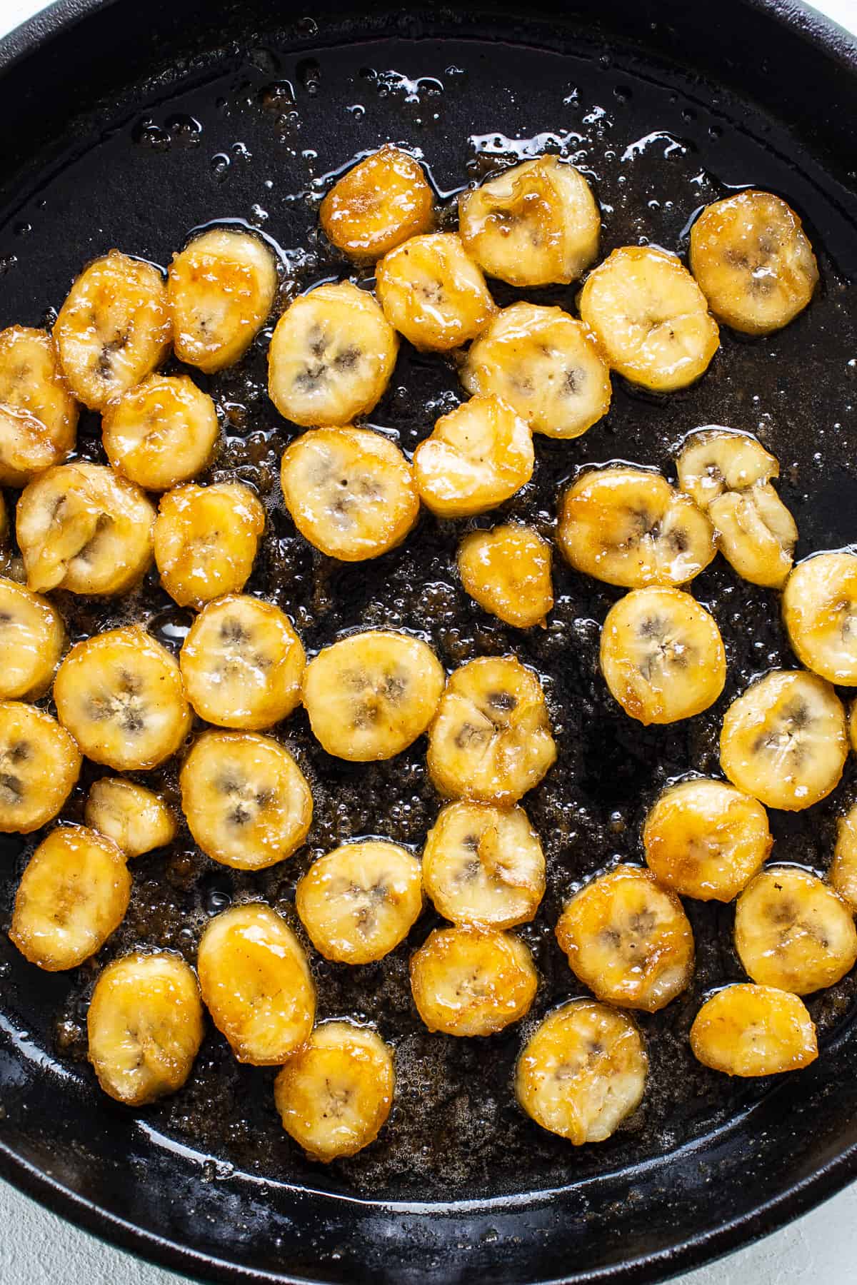 Sliced bananas are being fried in a skillet.