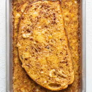 A slice of french toast in a pan on a white surface.