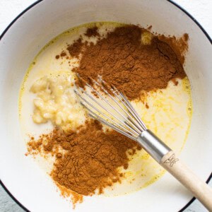 A bowl with cinnamon, sugar, and a whisk.