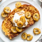 A plate of french toast with bananas and whipped cream.