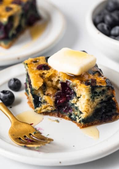 Blueberry breakfast cake on a plate with a gold fork.